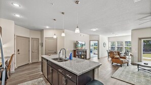 A spacious kitchen with a central island, dark cabinetry, and a large window providing natural light.