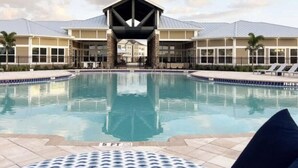 A swimming pool with a covered area and lounge chairs.