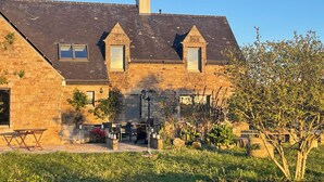 A stone house with a sloped roof, a chimney, and a small front porch with outdoor seating. - Romantic mini villa - heated pool and wooded park -Les Hauts de Locmiquel (Baden)