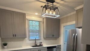 A modern kitchen with grey cabinets, stainless steel appliances, and a black countertop. - Fully renovated Charming 2-bedroom with full kitchenin amazing at1423 Madison av (Montgomery)