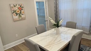 A dining room with a marble table, four grey chairs, a patterned rug, a ceiling fan, and a painting on the wall. - Fully renovated Charming 2-bedroom with full kitchenin amazing at1423 Madison av (Montgomery)