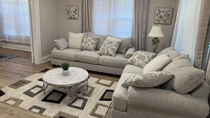 A living room with a sectional sofa, a round coffee table, and a floor lamp. - Fully renovated Charming 2-bedroom with full kitchenin amazing at1423 Madison av (Montgomery)