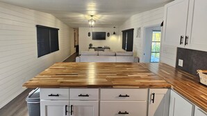 A modern kitchen with white cabinetry, a wooden countertop, and a built-in bench. - Slice of Paradise w/community pool near beaches & downtown! (Fort Myers)
