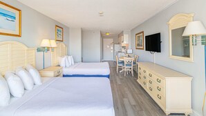 Ein Hotelzimmer mit zwei Betten, einem Schreibtisch, einem Stuhl, einer Kommode und einem Fernseher.