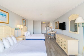 Habitación de hotel con dos camas, un escritorio, una silla, un aparador y un televisor.
