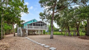 A house with a covered porch, a gravel driveway, and a wooden deck. - 3-bedroom Riverfront home with private boat dock and view of Steinhatchee River. (Steinhatchee)