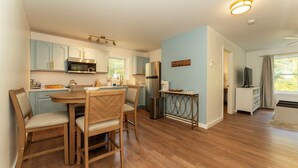 Une cuisine moderne avec des meubles en bois, une table à manger avec des chaises, un four à micro-ondes encastré et un réfrigérateur.