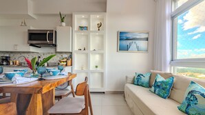 Une cuisine moderne avec un coin repas, un canapé avec des coussins bleus et une vue sur l’extérieur.