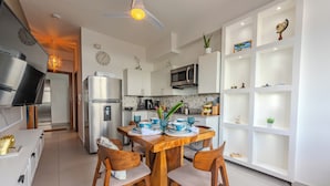 Une cuisine moderne avec des meubles blancs, une table à manger dressée avec de l’assiette bleue et blanche, et un ventilateur de plafond.