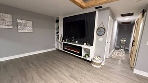 Ein modernes Wohnzimmer mit Flachbildfernseher, Holzboden und dekorativen Wandbildern.