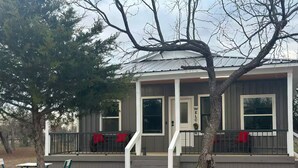 Ein zweistöckiges Haus mit Veranda, Treppe und einer kleinen Holzterrasse.