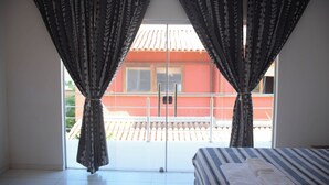 Una habitación con una cama, una ventana con cortinas y vista a un edificio.