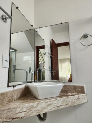 A bathroom with a white sink, a large mirror, and a marble countertop. - Oceano Sagrado (Porto Seguro)