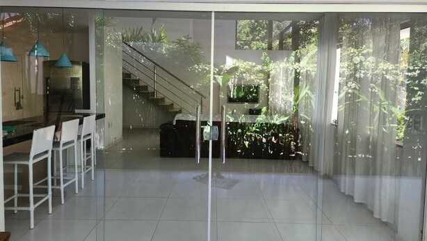 Una cocina moderna con sillas blancas, una escalera y vistas al exterior con vegetación.