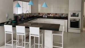 Una cocina moderna con armarios blancos, encimera negra y tres lámparas colgantes azules.