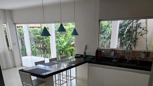 Una cocina moderna con una isla central, armarios blancos e iluminación colgante.