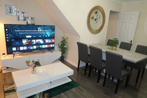 Relax in this stylish living room with a flat-screen TV, dining area, and comfortable seating.