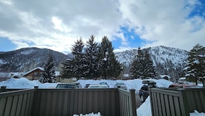 Un paysage de montagne enneigé, avec une clôture en bois au premier plan.