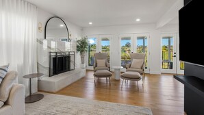 A spacious living room with a fireplace, two armchairs, a sofa, and a TV.