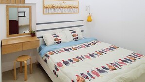 Een slaapkamer met een bed, een bureau, een stoel, een spiegel, een muurlamp en een lijst met een afbeelding.