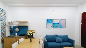 Een moderne woonruimte met een keuken, eethoek en een blauwe bank.