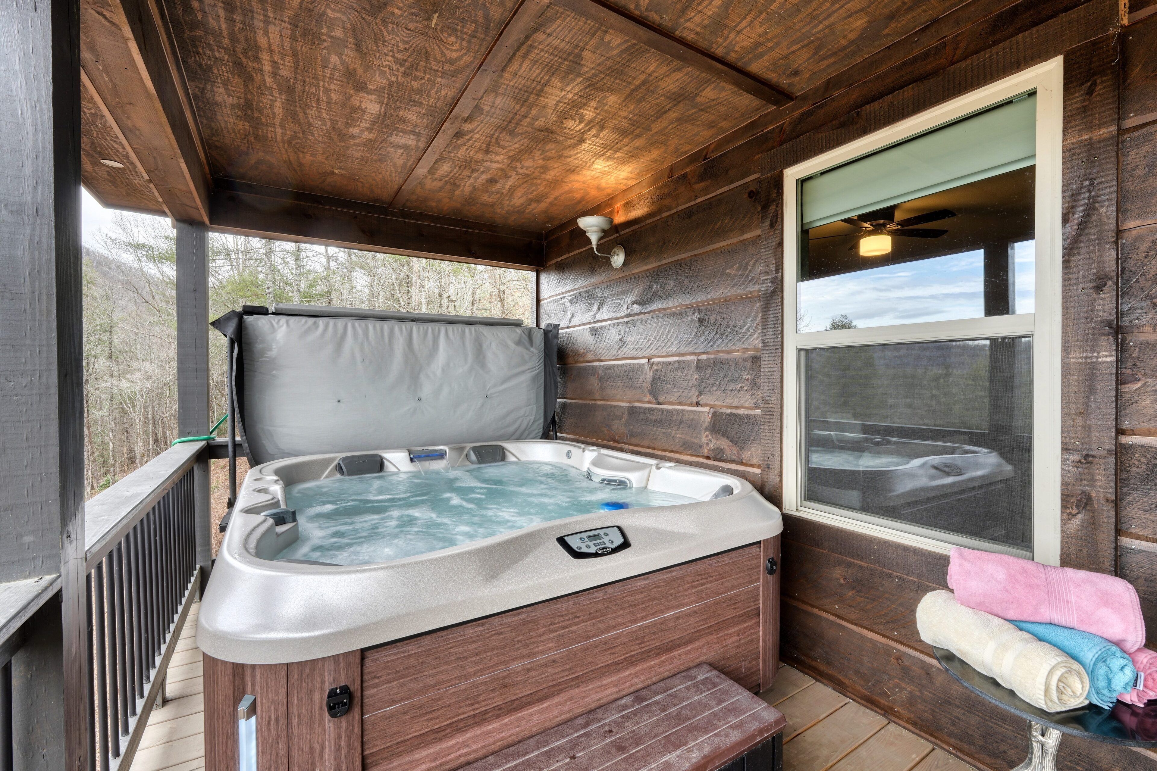 Une cabane en bois avec un bain à remous, une fenêtre et des serviettes sur une table.