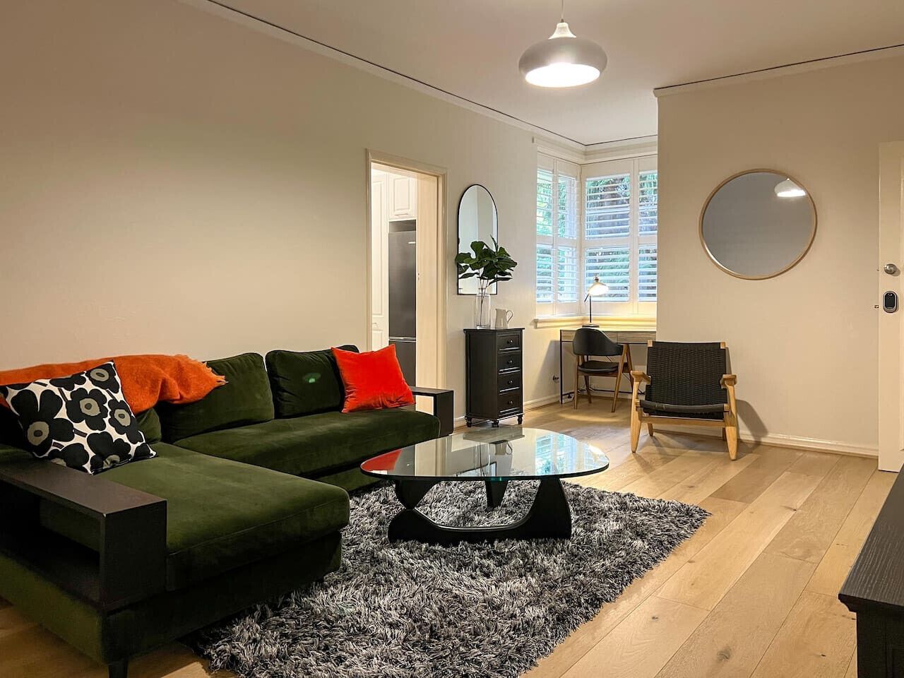 Un salon moderne avec un canapé vert, une table basse en verre et un fauteuil noir.