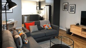 Een moderne woonkamer met een grijze bank, een bijzettafeltje en een tv-meubel.