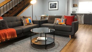 Een moderne woonkamer met een hoekbank, een salontafel en een trap.