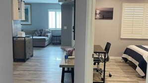 Un grand espace de vie comprenant un canapé, une table à manger et un coin cuisine avec des placards et un plan de travail.