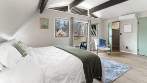 Un dormitorio con cama, una silla, una ventana y una puerta.