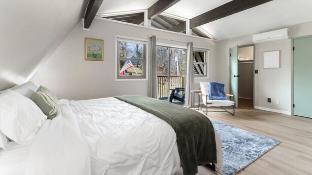 Une chambre à coucher avec un lit, une chaise, une fenêtre et une porte.