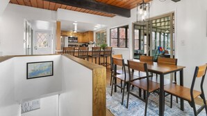 Un comedor amplio con mesas y sillas de madera, una cocina al fondo y un ventanal con vistas.