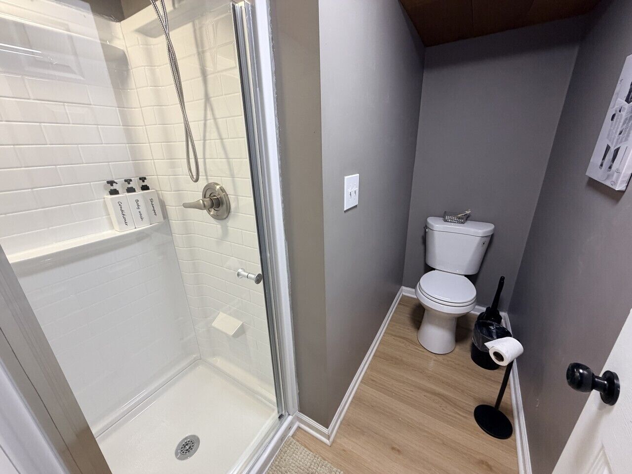 A bathroom with a glass shower enclosure, a toilet, and a sink.