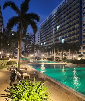 Ein Hotel mit Pool, Palmen und einem gut beleuchteten Außenbereich.