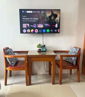Un televisor montado en la pared mostrando el programa 'Wicked: For Good', con una selección de íconos de servicios de streaming debajo.
