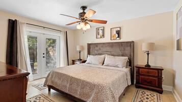 A bedroom with a bed, a ceiling fan, two bedside tables, and a window with curtains.