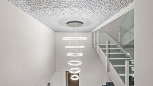 Un interior moderno con una escalera, un techo estampado y una serie de lámparas circulares.