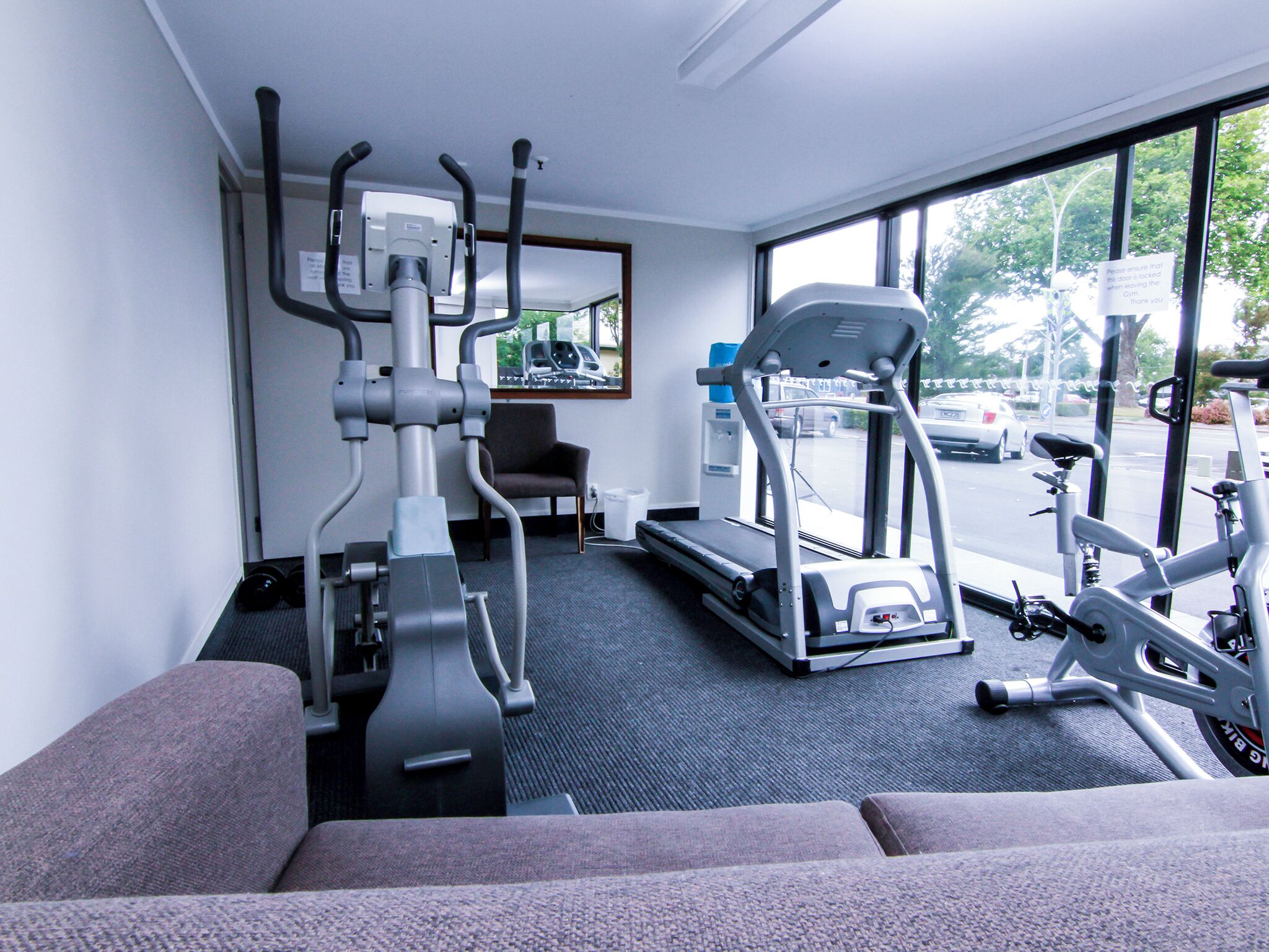 A gym with exercise equipment, a treadmill, and a chair.