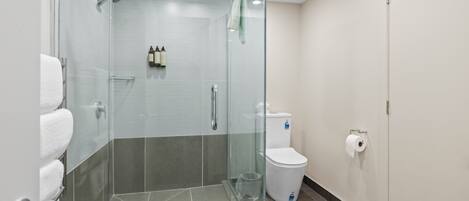 A modern bathroom with a glass-enclosed shower, a toilet, and a sink.