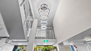 Un interior moderno con un diseño de techo único, un letrero de salida de emergencia visible y una pared de vidrio que ofrece vistas al exterior.