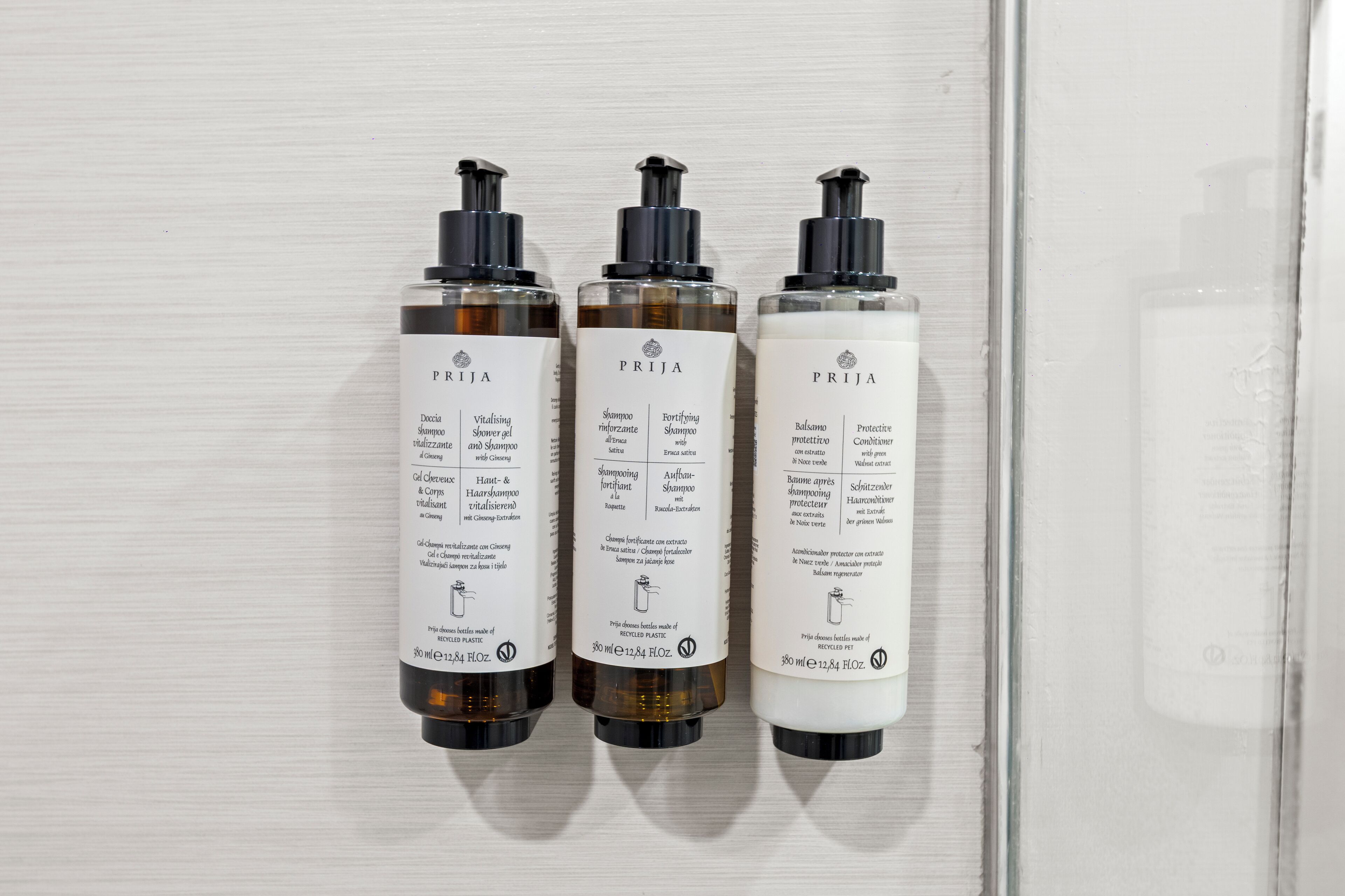 Three bottles of PRIZA hair care products on a white surface.