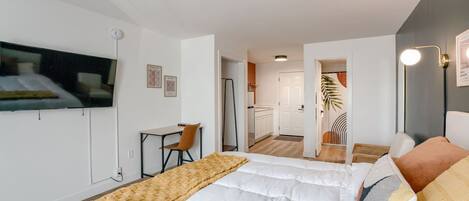 Hotellihuoneessa on sänky, työpöytä, tuoli, televisio ja pieni keittiönurkkaus.
