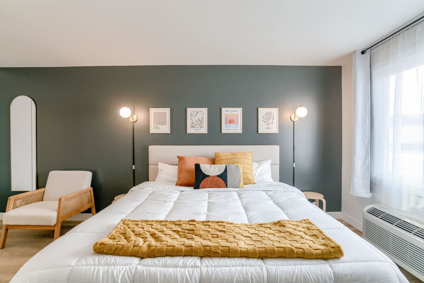 Un dormitorio con cama, una silla, decoración en la pared y una ventana.