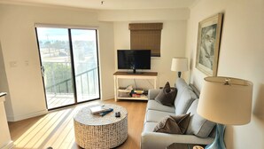 A living room with a sofa, a coffee table, a TV, a lamp, and a balcony with a view. - Myrtle Beach Resort (Myrtle Beach)