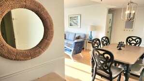 A dining area with a round woven mirror, a wooden table, and black chairs. - Myrtle Beach Resort (Myrtle Beach)