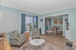 A living room with patterned sofas, a coffee table, and a dining area with chairs and a table. - Myrtle Beach Resort (Myrtle Beach)