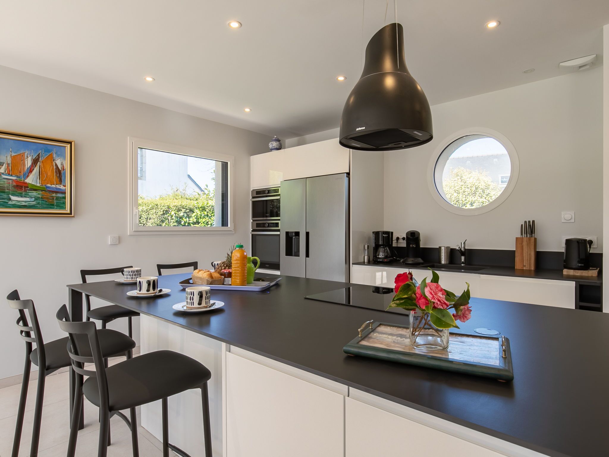 Una cocina moderna con una isla central, electrodomésticos de acero inoxidable y un amplio ventanal que proporciona luz natural.