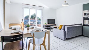 A modern apartment with a dining area, a sofa, a TV, and a kitchen. - Malibu Village by Interhome (Canet-Plage)