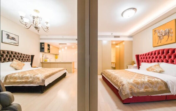 A hotel room with a large bed, a separate sitting area, a chandelier, and a view of the kitchen. - qingdaowanxianghuayuan (Qingdao)